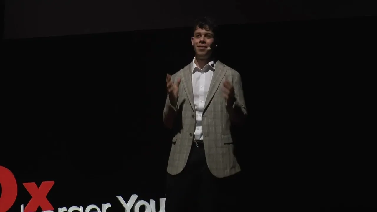 Vinny on the TEDxHensemberger Youth stage, mid-sentence, in a checked jacket